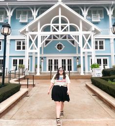 a woman is standing in front of a blue building with white trim and arched windows