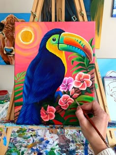 a person is painting on an easel with flowers and a toucan