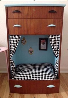 a child's bed made out of a wooden cabinet with black and white checkered sheets