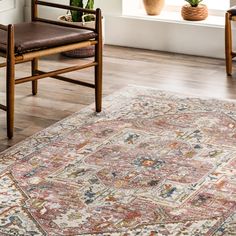 a large rug in the middle of a room with two chairs and a potted plant