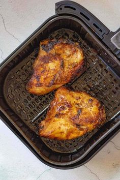 two pieces of chicken cooking in an air fryer