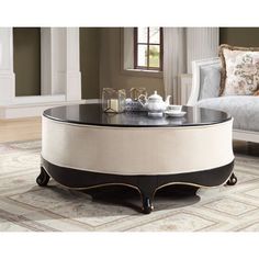 a round coffee table with an ottoman in the middle and a tray on top that has tea set on it