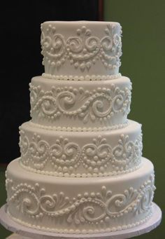 a three tiered white wedding cake sitting on top of a table next to a mirror