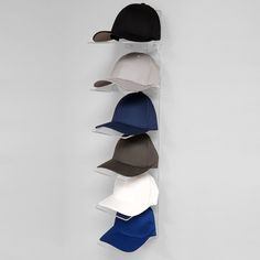 five hats are hanging on the wall and one hat is in front of the other