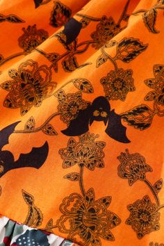 an orange fabric with black birds and flowers on it