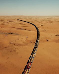 a train traveling through the desert with no one on it's tracks or cars