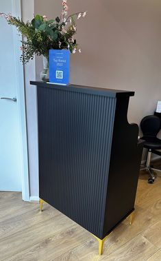 a black and yellow reception desk with a blue vase filled with flowers next to it