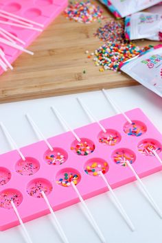 pink ice cream tray with sprinkles and candy lolly pops on it