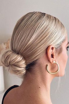 a woman with blonde hair in a low bun wearing large gold hoop earrings