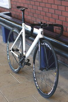 a white bicycle parked next to a brick wall