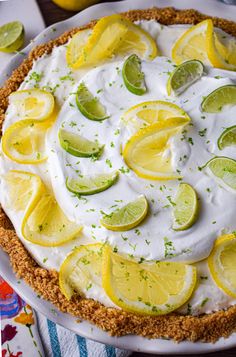 a pie with lemons, limes and whipped cream on it sitting on a table