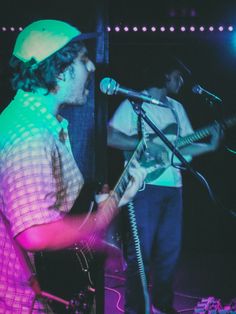 two men are singing into microphones while playing guitar