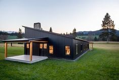 a small black house sitting on top of a lush green field