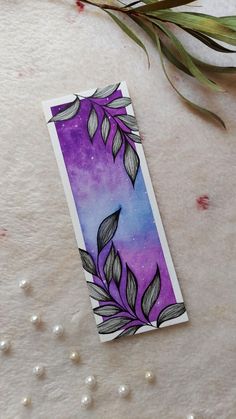 a purple and blue bookmark sitting on top of a white table next to pearls