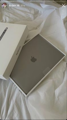 an apple laptop in its box on a bed