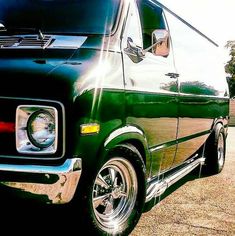 an old black van parked in a parking lot with the sun shining on it's windows