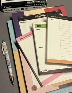 several notebooks and pens on top of each other with the same item in front of them