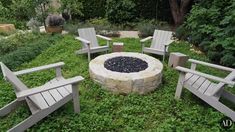 a fire pit surrounded by wooden chairs in the middle of a grassy area with trees and bushes