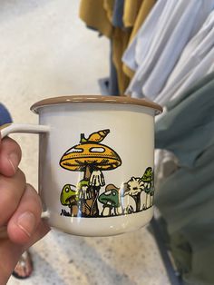 a hand holding a coffee cup with mushrooms painted on it