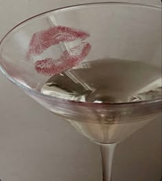 someone holding up a martini glass with lipstick drawn on it