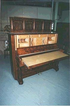 an old piano is sitting in the middle of a room with blue flooring and white walls