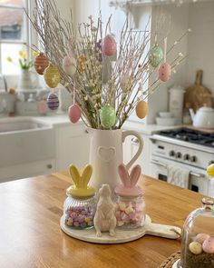 a vase filled with easter eggs on top of a wooden table next to an oven