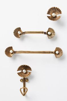 two antique brass door handles with pearls on each one and an arrow shaped finial