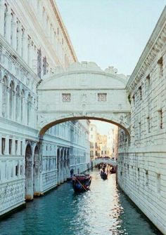 two boats are going under an overpass on a canal in venice, italy during the day