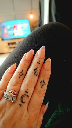 a woman's hand with two tattoos on her fingers and the other half of her finger