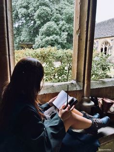 a woman sitting on a window sill holding a pen and paper in her hand