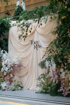 an outdoor stage set up with flowers and greenery for a wedding or special event