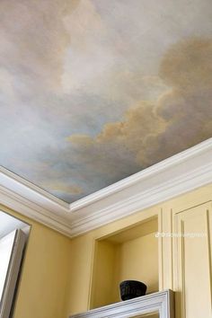 the ceiling is painted with a sky painting on it's wall and there is a mirror in front of it