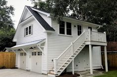 a two story white house with stairs leading up to it