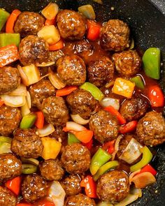 meatballs and vegetables are being cooked in a skillet