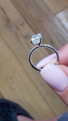 a woman's hand holding a ring with a diamond on it and a pink manicure