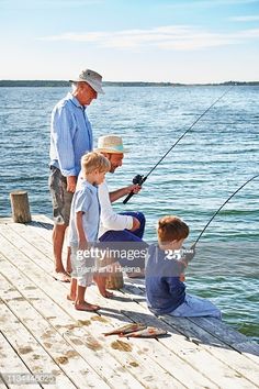 an older man and two young boys fishing on the dock with their dad stock photo