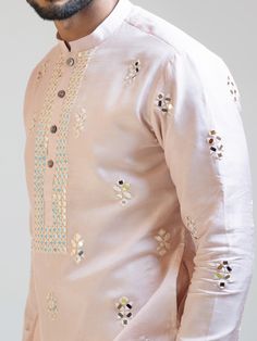 This Baby Pink Mirror Work kurta set will instantly give an elegant look. This 2 piece kurta set features a bam silk baby pink kurta, mirror work embroidery, front buttons fastening, and a mandarin collar. It is paired with narrow fitted pajama pants in cream color and malai cotton fabric. An ideal outfit for traditional occasions, and special events.

Size Chart For Men





	
	
					Men's Size Chart
		

		
		
						
				Size Chart For Men
				Custom Size Measurement Guide Spring Cotton Silk Sets With Mirror Work, Spring Festive Cotton Silk Sherwani, Bollywood Style Kurta With Mirror Work For Spring, Cotton Sherwani With Dabka Work For Spring, Spring Cotton Silk Kurta With Zari Work, Spring Cotton Silk Sherwani With Zari Work, Spring Festive Silk Sherwani, Silk Sherwani With Zari Work For Spring, Spring Cotton Traditional Wear With Mirror Work