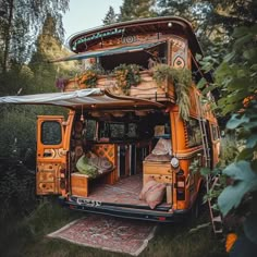 an orange bus is parked in the woods with plants growing on it's roof