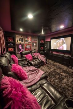 a home theater with black leather couches and pink throw pillows on the carpeted floor