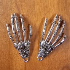 two metal skeleton hand key chains on a wooden surface