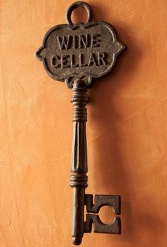 an old style wine bottle opener hanging on a wall with the word wine cellar written on it