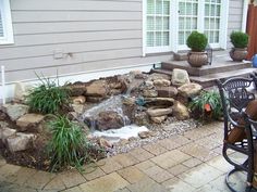 an outdoor patio with a waterfall and chairs