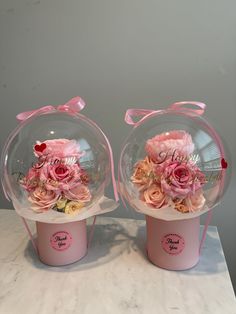 two clear vases with pink flowers in them