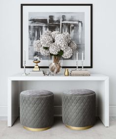 two stools with flowers and candles on them in front of a white console table