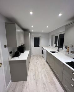 an empty kitchen with white counter tops and gray cupboards on either side of the stove