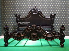 an ornate bed frame in the corner of a room with polka dot wallpaper and green carpet