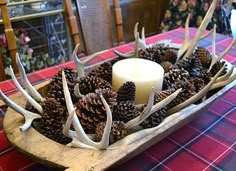 a candle and antlers in a wooden bowl on a table