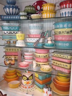 many bowls and plates are stacked on shelves