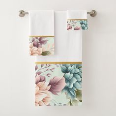 two white towels hanging on a towel rack with flowers painted on them and gold trimmings