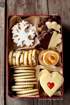 a red box filled with cookies and pastries sitting on top of a wooden table